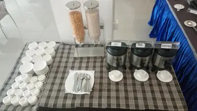 a table with cups and plates and utensils at Sara Hotels and Apartments in Nedumbassery
