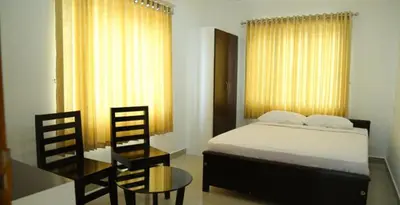 a bedroom with a bed and a table and chairs at Sara Hotels and Apartments in Nedumbassery