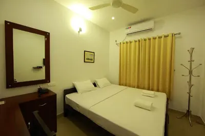 a small bedroom with a bed and a mirror at Sara Hotels and Apartments in Nedumbassery