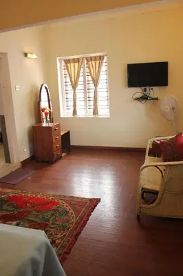a living room with a television and a couch and a window at Colonels inn in Ooty