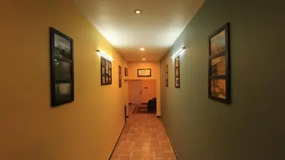 a long hallway with paintings on the walls at The Black Magic Cottage in Ooty