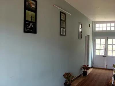 a room with a white wall with pictures on it at The Black Magic Cottage in Ooty