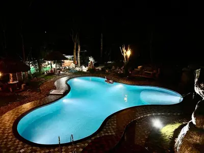 a large blue swimming pool at night at Pugmarks Jungle Resort in Chekadi