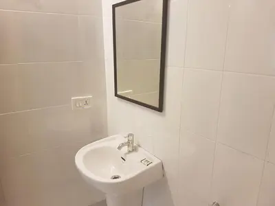 a white bathroom with a sink and a mirror at Petit Elephant in Cherai Beach