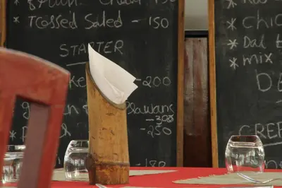 a wooden napkin holder on a table in front of a blackboard at Petit Elephant in Cherai Beach