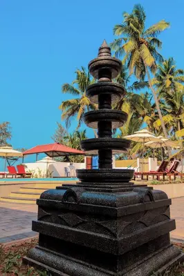 a black fountain with palm trees in the background at Petit Elephant in Cherai Beach