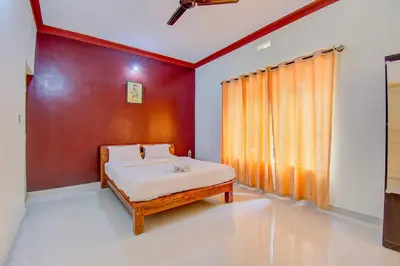 a bedroom with a bed and a red wall at Holidayincoorg Orchid Villa in Madikeri