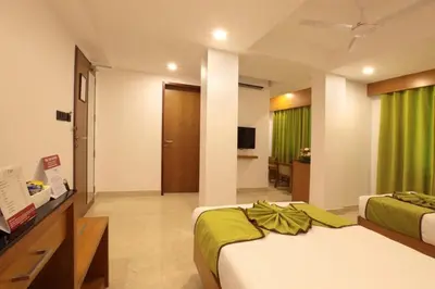 a bedroom with two beds and a television in it at Hotel Park Residency Calicut in Kozhikode