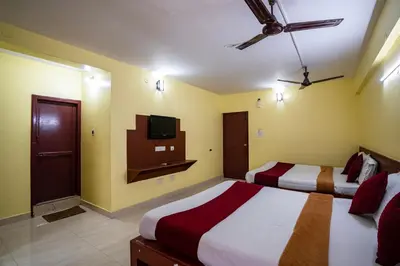 a bedroom with two beds and a tv on the wall at Hotel Vyshak residency in Mysore