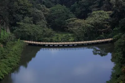 a bridge over a river with a reflection in the water at The IBNII - Eco Luxury Resort in Madikeri