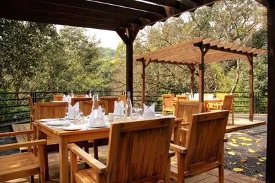 a wooden table and chairs on a patio at The IBNII - Eco Luxury Resort in Madikeri