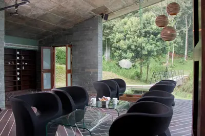 a room with chairs and a table and a large window at The IBNII - Eco Luxury Resort in Madikeri