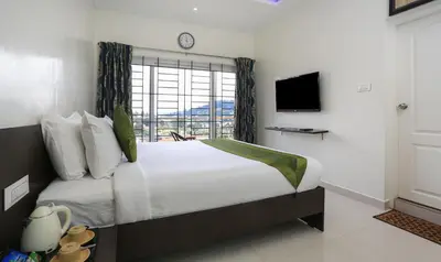 a bedroom with a large bed with a large window at Treebo Light House, 900 Mtrs From Botanical Garden in Ooty