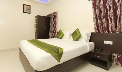 a bedroom with a bed with white sheets and green pillows at Treebo Light House, 900 Mtrs From Botanical Garden in Ooty