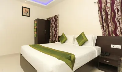 a bedroom with a bed with white sheets and green pillows at Treebo Light House, 900 Mtrs From Botanical Garden in Ooty