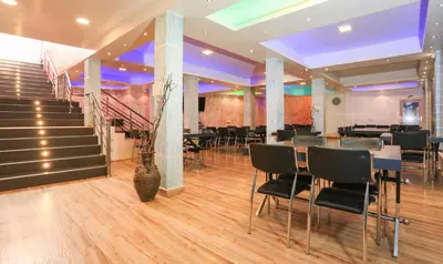 a dining room with tables and chairs and a staircase at Treebo Light House, 900 Mtrs From Botanical Garden in Ooty