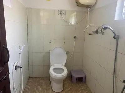 a small bathroom with a toilet and a shower at Golf Dale Holiday Resort in Kotagiri