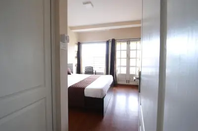 a bedroom with a bed and a large window at The Hill Side in Ooty