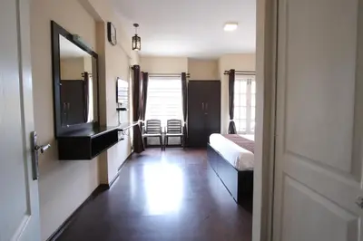 a hotel room with a bed and a mirror at The Hill Side in Ooty