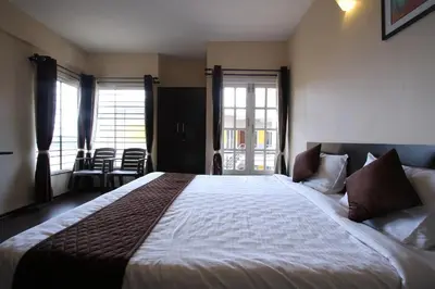 a bedroom with a large bed and two windows at The Hill Side in Ooty