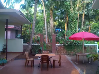 a patio with a table and chairs and a pink umbrella at Ivory Coaste in Kannur