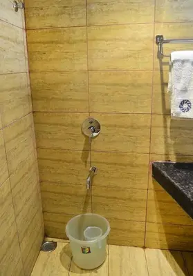 a toilet in a room with a bucket at Ranis Grand in Coimbatore
