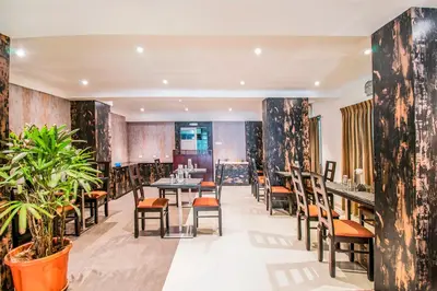a restaurant with tables and chairs and plants at FabHotel Jansi Deluxe - Nr Gandhipuram Bus stand in Coimbatore