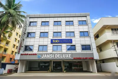 a tall building with a janish delivery sign on it at FabHotel Jansi Deluxe - Nr Gandhipuram Bus stand in Coimbatore