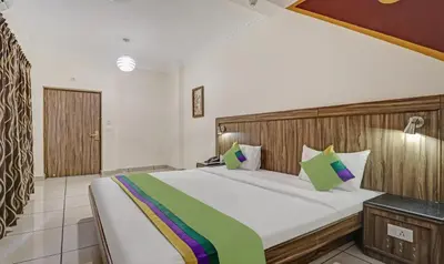 a bedroom with a large bed with a wooden headboard at Treebo Komfort Suites, 3 Km From Mysore Palace in Mysore