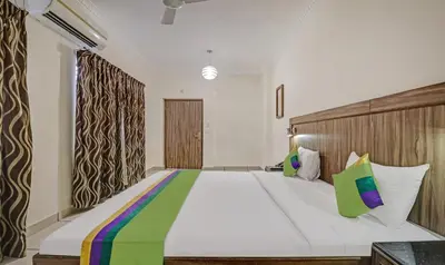 a bedroom with a large white bed with colorful pillows at Treebo Komfort Suites, 3 Km From Mysore Palace in Mysore