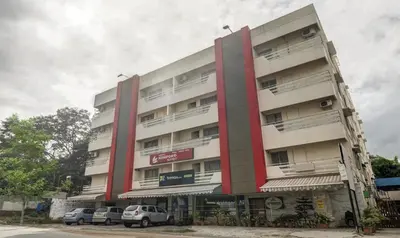 a tall building with cars parked in front of it at Treebo Komfort Suites, 3 Km From Mysore Palace in Mysore