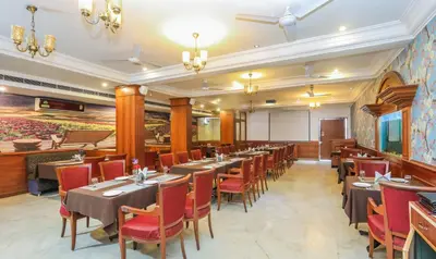 a dining room with tables and red chairs at Treebo Komfort Suites, 3 Km From Mysore Palace in Mysore
