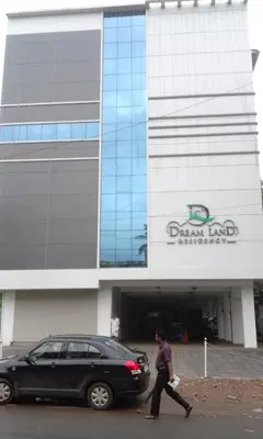 a man walking past a car in front of a building at Dream Land Residency in Mananthavady