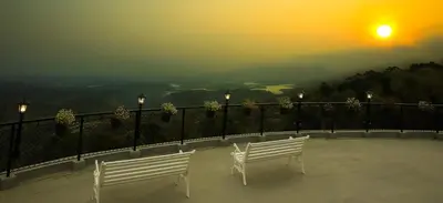 two white benches sitting on a balcony watching the sunset at Mount Xanadu Resorts in Ambalavayal