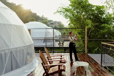 a woman standing on a deck taking a picture at Mount Xanadu Resorts in Ambalavayal