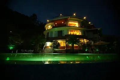 a building at night with a pool in front of it at Mount Xanadu Resorts in Ambalavayal