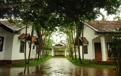 a row of trees in front of a house at Carpe DiemStay in Kushālnagar
