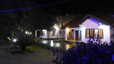 a house at night with blue flowers in the foreground at Carpe DiemStay in Kushālnagar