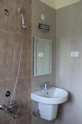 a bathroom with a sink and a shower with a mirror at Golden Springs in Ooty