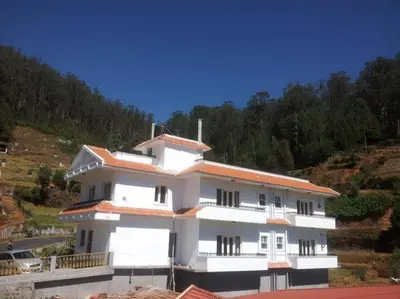 a white building with an orange roof on a hill at Golden Springs in Ooty