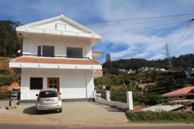a car parked in front of a white house at Golden Springs in Ooty