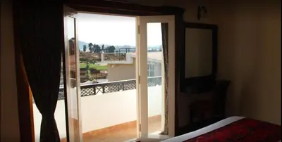 a room with a window with a view of a balcony at Golden Springs in Ooty