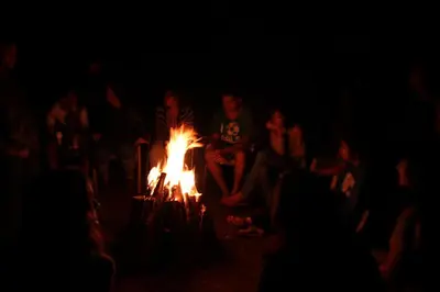 a group of people sitting around a fire in the dark at Misty Woods Resort in Kakkabe