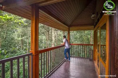a man is standing on a porch on a house at Wild Planet Jungle Resort in Devāla