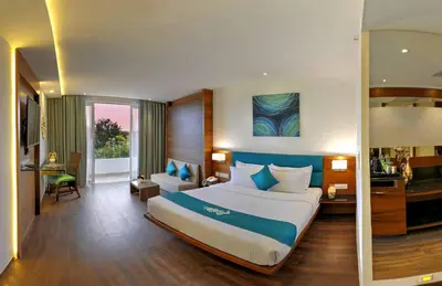 a hotel room with a large bed and a desk at Roopa Elite in Mysore