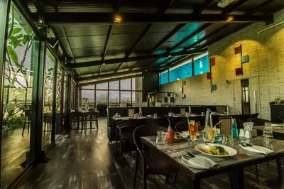 a dining room with tables and chairs and windows at Roopa Elite in Mysore