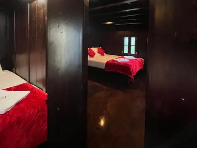 two beds in a small room with red sheets at NATURE CASTLE -Traditional villa,Vattavada in Kottakamboor