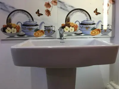 a white sink in a bathroom with butterflies on a shelf at Kvm Tourist Home in Palakkad