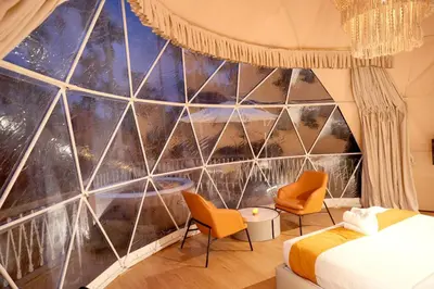 a bedroom with a large glass wall at Le Villagio Resort & Domes in Sultan Bathery