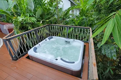 a hot tub sitting on a deck with plants at Le Villagio Resort & Domes in Sultan Bathery